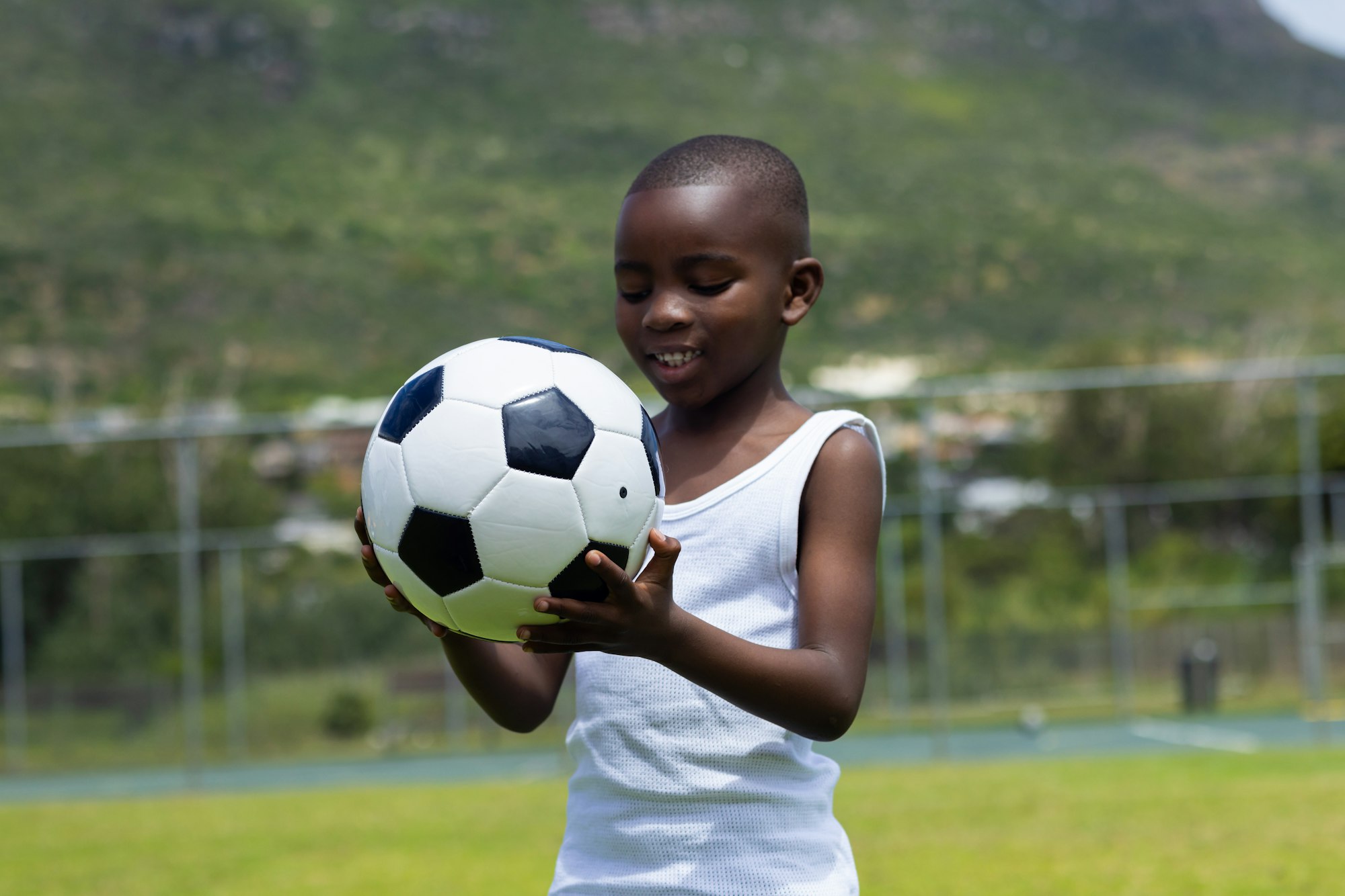 African American boy holds a soccer ball outdoors in school