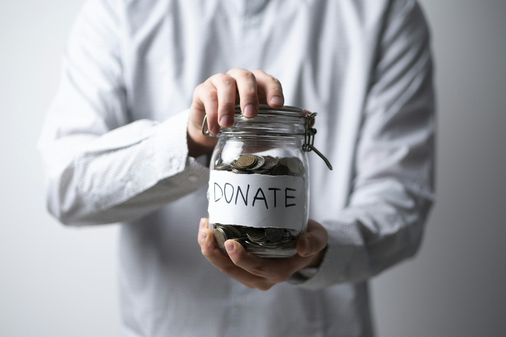 a person holding a glass jar with metal coins, money donations concept